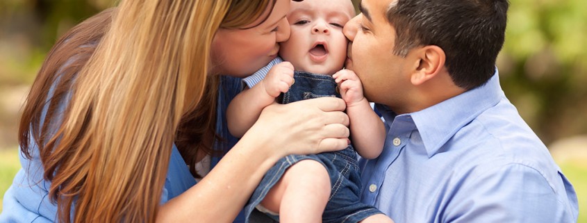 parents hold and kiss baby