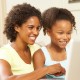 mother and daughter laughing at image on computer