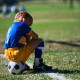 boy sits on soccer ball on sideline