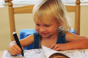 young girl drawing in coloring book