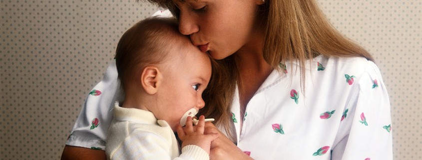 mother holds and kisses baby