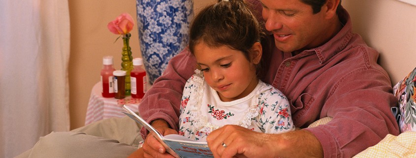 father reads to daughter in bed