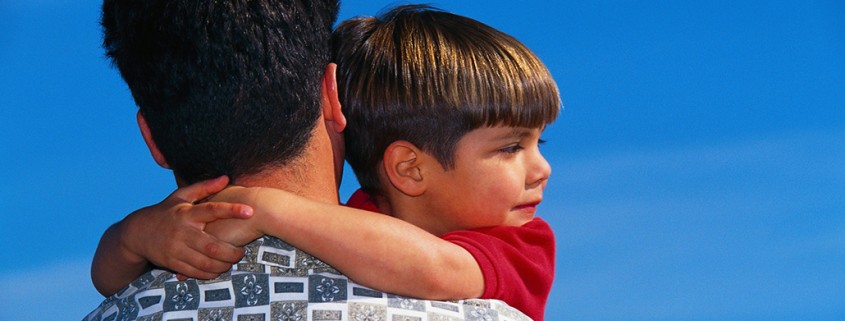 boy with arms around the neck of father