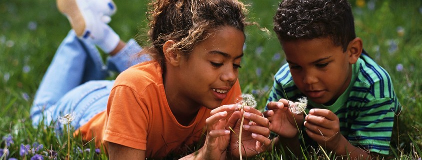 boy and girl play with dandelions