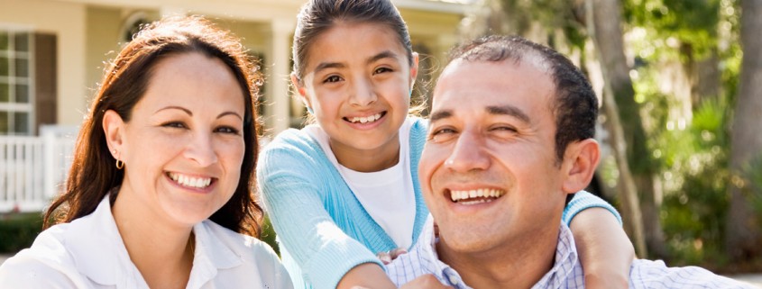 family of three in front of house