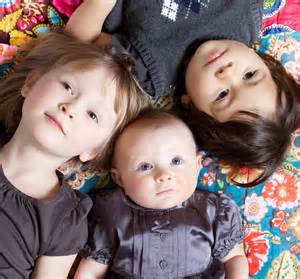 two small children and a baby laying on bed