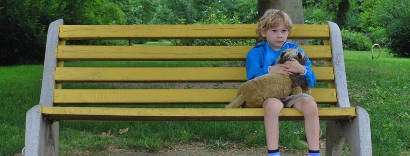 boy and stuffed toy dog sitting on a park bench