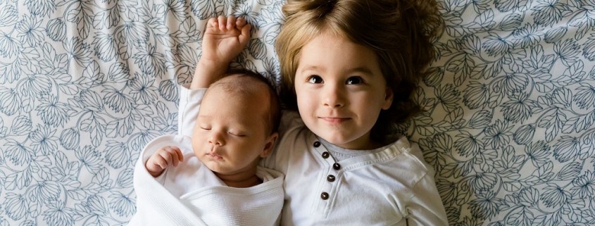 very young boy and babay laying on a bed