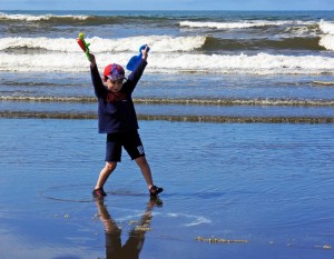 young boy plays at the ocean's edge