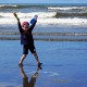 young boy plays at the ocean's edge