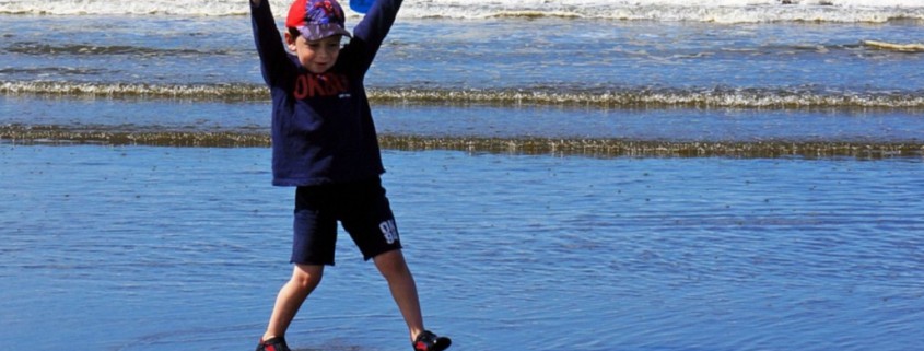 young boy plays at the ocean's edge