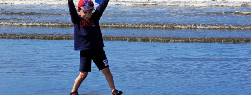 young boy plays at the ocean's edge