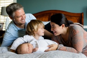 young family sharing a laugh on a bed