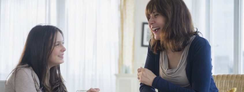 Teenage girl (14-15) talking with her mom in living room