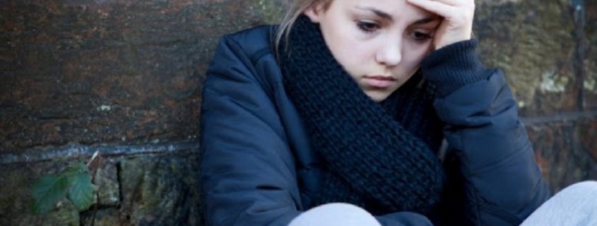 upset teenage girl sitting outside in the cold