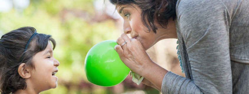 mother blowing up balloon for daughter