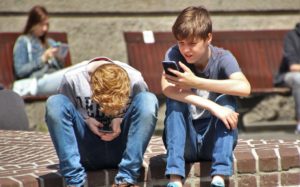 boys playing pokemon go on phones