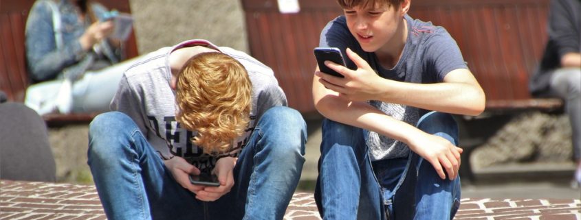 boys playing pokemon go on phones