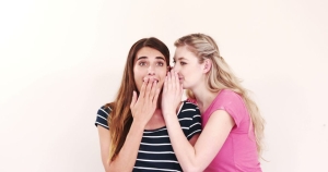 One girl talking into another girls ear