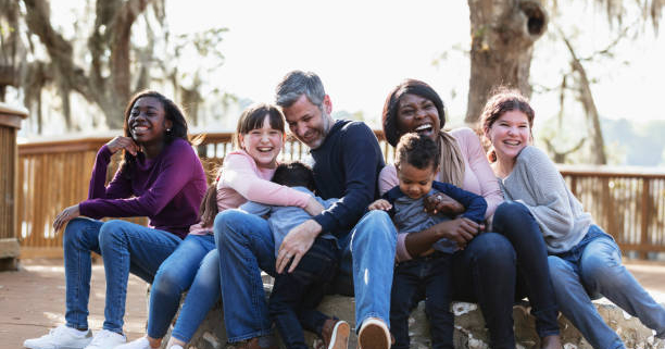 A multi-ethnic blended family playing in the park together on a sunny day.